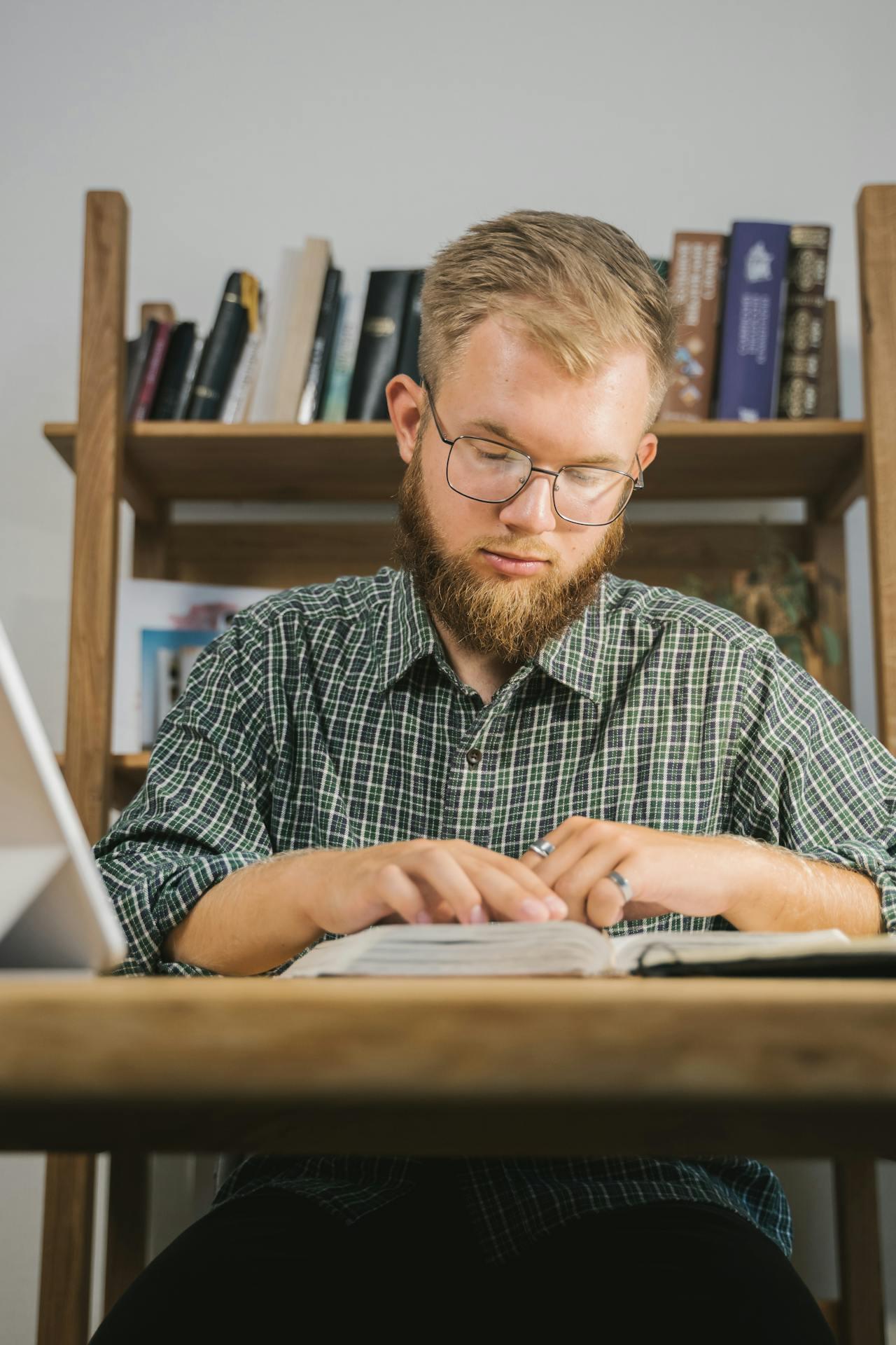 Человек читает книгу за рабочим столом